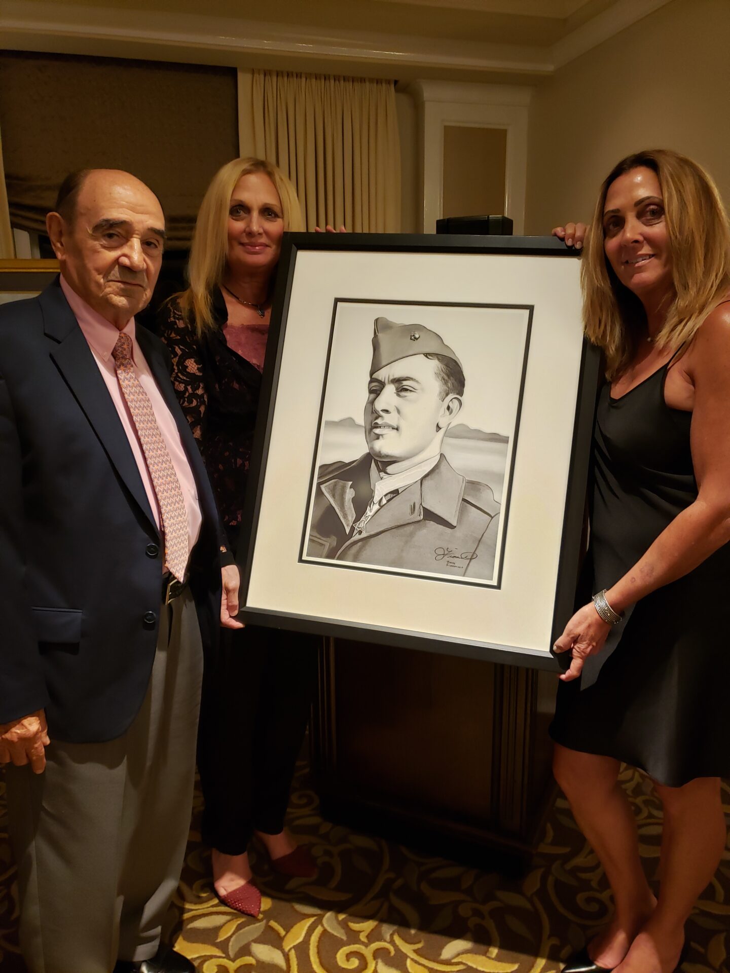 From left Donald Basilone, brother of John Basilone, Diane Hawkins, and Kim Van Note, nieces of John Basilone, hold a portrait of Sgt. John Basilone painted by Artist James Fiorentino.